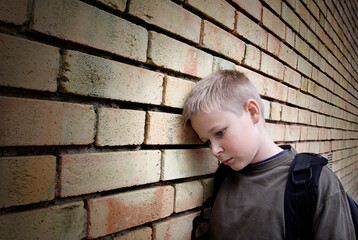 upset boy leaning against a wall