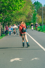 Young girl rollerblading down the street on a sunny spring day, young people with bikes in the park, healthy lifestyle concept, sustainable eco friendly urban transport. Copy space