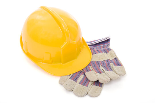 Yellow safety helmet and a pair of industrial protective gloves over white background
