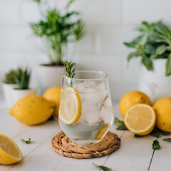 Água com gelo e rodela de limão em fundo de madeira branca