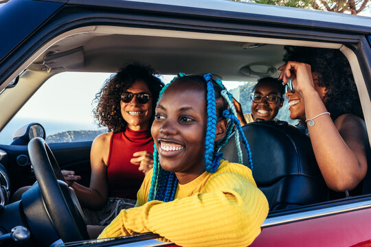 Cheerful diverse girlfriends riding in car