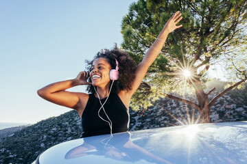 Cheerful black woman listening to music in headphones