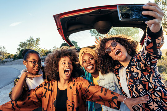 Happy black women taking selfie near car