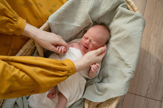 Woman putting infant to sleep in bassinet