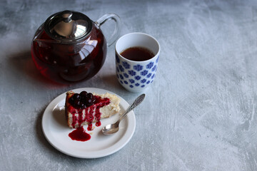 A piece of cherry cheesecake on a white plate and a teapot. Close up photo of homemade dessert. Sweet food concept. 