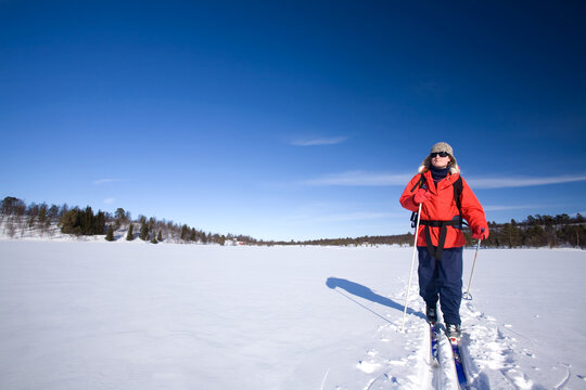 A woman cross country skiing across a frozen lake