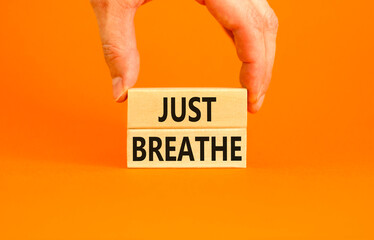 Just breathe and psychological symbol. Concept words Just breathe on beautiful wooden block. Beautiful orange background. Businessman hand. Business psychological and Just breathe concept. Copy space