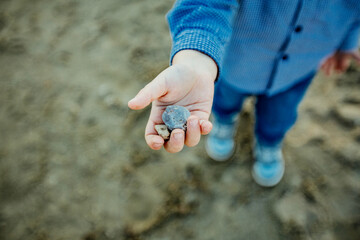 Dłoń małego chłopca trzymającego kamyki i bawiącego się na dworze