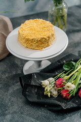 Freshly made delicious puff pastry napoleon cake on a white stand on a background of flowers...