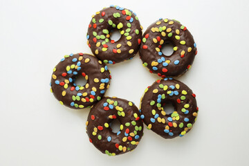 A set of doughnuts glazed with chocolate and colorful smarties. Five donuts isolated on a white background. Side view. Copy space