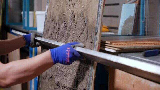 A man with an even long spatula cement dry mixture on the wall. Close-up. Align the cement mixture with a special tool