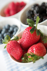 Bowls of summer berries - strawberries, blackberries, blueberries &  raspberries - shallow dof