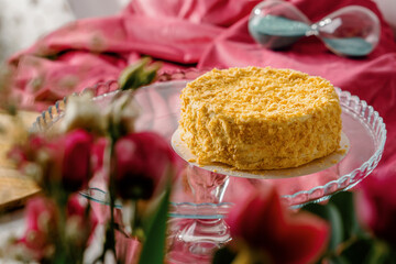 Freshly made delicious puff pastry napoleon cake on glass stand on bright pink background close-up...