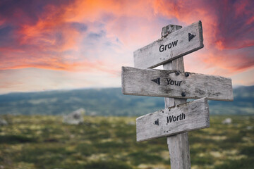 grow your worth text quote on wooden signpost outdoors in nature. Pink dramatic skies in the background. - obrazy, fototapety, plakaty