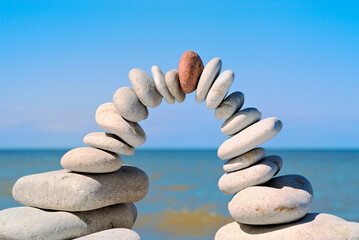 Stone arch with red stone at top in the morning on a beach