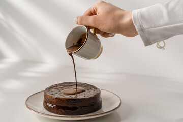 delicious freshly made chocolate sacher cake on a plate on a white background drizzled with hot chocolate dessert concept