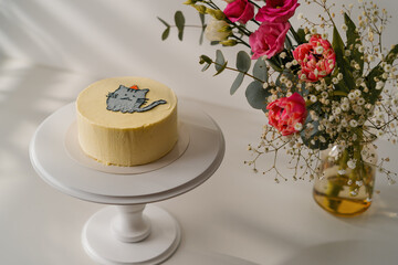 delicious freshly made biscuit bento cake with a painted cat standing on a stand on a white background with flowers