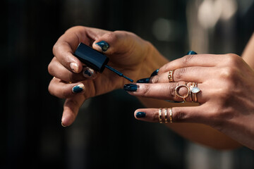 Female hands painting her messy nails with a brush.