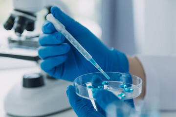 Fototapeta premium Medical Development Laboratory: Caucasian Female Scientist Looking Under Microscope, Analyzes Petri Dish Sample. Specialists Working on Medicine, Biotechnology Research in Advanced Pharma Lab