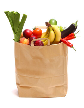 A grocery bag full of healthy fruits and vegetables on white