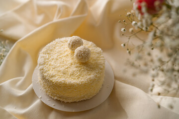 delicious freshly made cream sponge cake decorated with candies from coconut shavings on a background of flowers