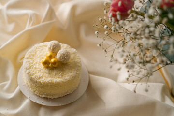 delicious freshly made cream sponge cake decorated with candies from coconut shavings on a background of flowers