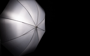 White silver reflective photo umbrella on a black background