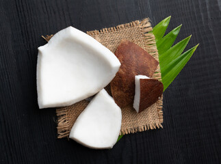 Pieces of coconut with leaves on wooden table