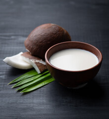 Coconut and coconut milk in wood bowl on wooden table