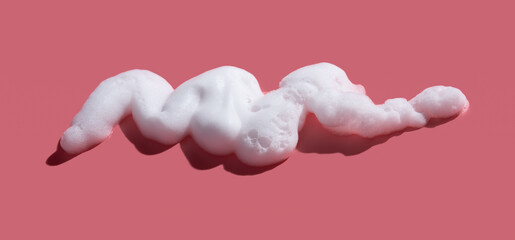 White soap foam, suds of detergent, cleaning gel or shampoo on pink backdrop