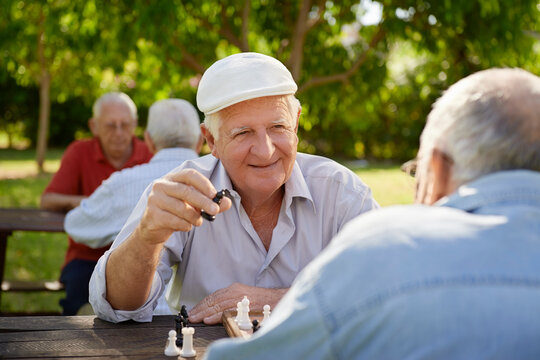 Active retired people, old friends and free time, two seniors having fun and playing chess game at park. Waist up