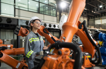 After installing a program on the robotic arm, a female engineer with a robotic arm controller...