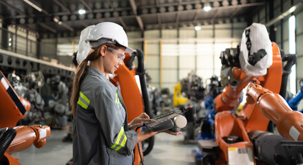 After installing a program on the robotic arm, a female engineer with a robotic arm controller...
