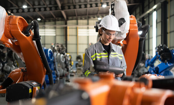 After installing a program on the robotic arm, a female engineer with a robotic arm controller performs a test run.