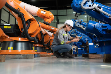 In the robots warehouse, A female engineer inspects the electrical system of every robotics arm,...