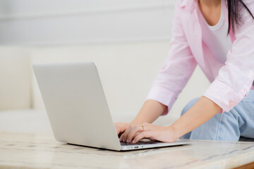 Young asian business woman work from home with laptop computer online to internet on sofa in living room, freelance is female using notebook sitting on couch with comfort and relax, lifestyle concept.