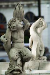 Sculpture at one of the cardinal points of a fountain with a cherub on a fish and carrying a barnacle