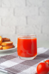 Glass of tomato juice with vegetables on white brick wall background