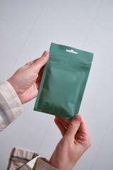 Kraft green paper packaging in female hands. Packaging for coffee, cosmetics. Packing close-up. Product for sale. Online shopping. Surprise boxes. Delivery service, delivery. Empty, mockup
