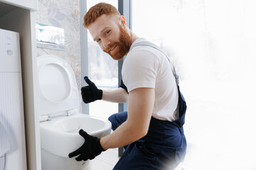 Man plumber installing white hung toilet on wall. Concept repair service plumbing in bathroom