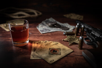 Poker at the Old Western Saloon Table with playing cards, whiskey and weapons - 600839084