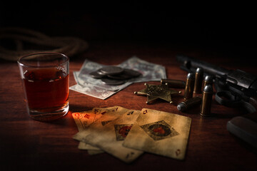 Poker at the Old Western Saloon Table with playing cards, whiskey and weapons - 600839097
