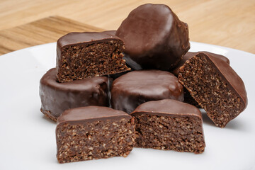 Natural nut chocolate dessert on a white plate on a wooden table. 