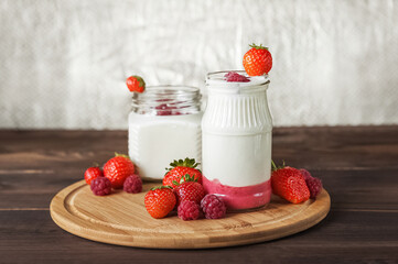 Strawberry raspberry yogurt in jar on wooden board close-up and copy space