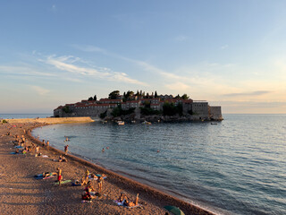 Tourists sunbathe on a sandy beach near the isthmus to the island of Sveti Stefan. Montenegro