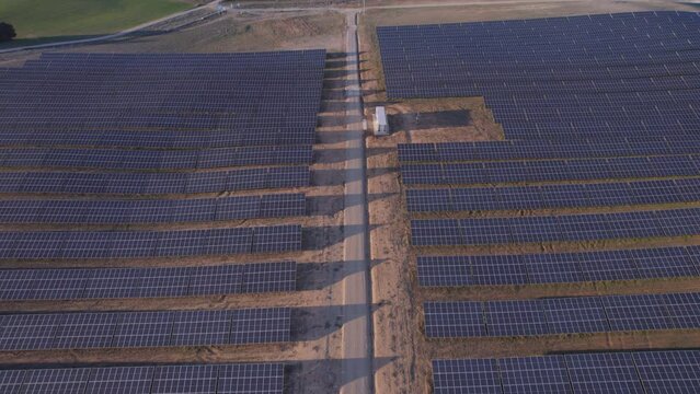 Aerial view of the road in a Solar Power Station with solar panels on the side of the road producing electricity sustainable energy at sunset. Power plant producing green solar energy, Spain