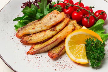 Fried Tilapia fish fillet, in spices, with cherry and salad, on a white plate, homemade, no people,