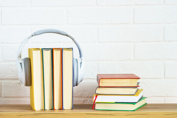Fototapeta na wymiar Audio books concept. Wireless Headphones and color books at wooden table white background.