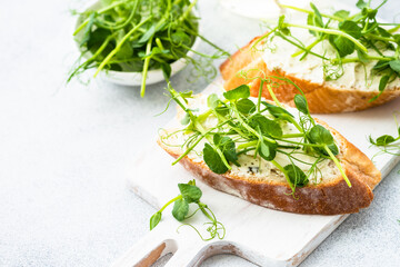 Toast with micro greens, green pea and cream cheese at blue. Healthy food snack, vegetarian. Close up.