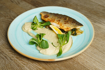 Fried branzino fish fillet with artichoke cream and fried pak choi with sesame seeds